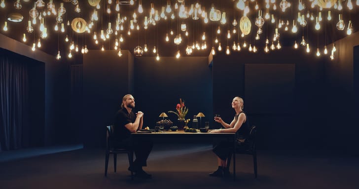 Un couple est assis à la table à manger sous un ciel étoilé fait de nombreuses lampes