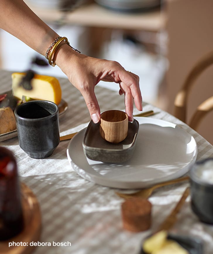 Une main arrange de la vaisselle sur une table dressée.