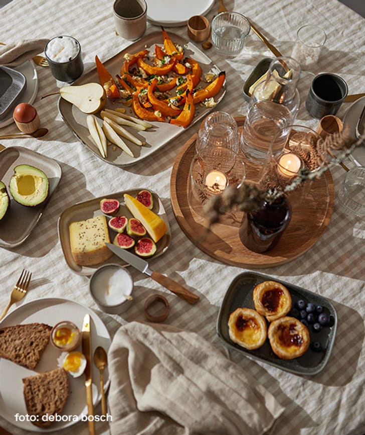 Verschiedene Gerichte und Früchte auf einem gedeckten Tisch.