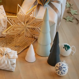 Décorations et cadeaux sur un sol en bois, y compris une étoile et de petits arbres.