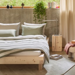 Chambre moderne avec lit en bois, coussins verts et plantes sur le rebord de la fenetre.
