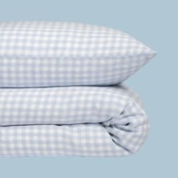 Coussin et couette à carreaux bleu et blanc empilés l&amp;apos;un sur l&amp;apos;autre.