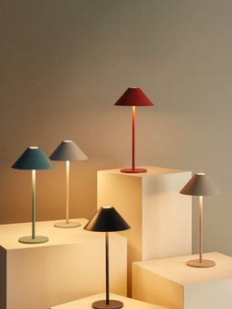 Cinq lampes de table colorées avec abat-jours coniques sur des socles clairs.