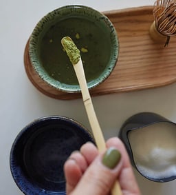 Matcha-Pulver auf einem Bambuslöffel vor einer Schale.