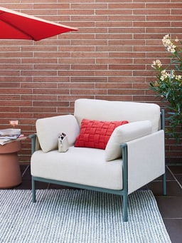 Fauteuil lounge confortable avec coussin rouge sur la terrasse.