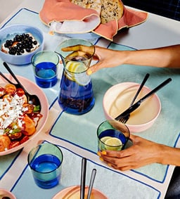 Table avec des plats frais et des boissons dans des verres colorés.