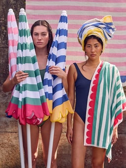 Deux personnes avec des parasols rayés colorés et des serviettes.