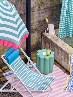 Espace détente avec chaise longue, parasol et petite table.