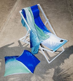 Chaise longue avec une serviette bleue et des coussins sur le béton.