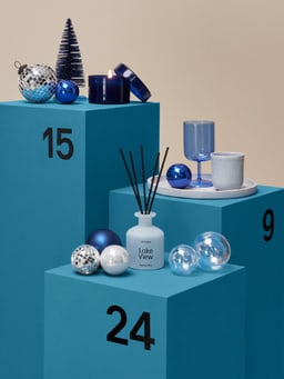 Calendario dell&apos;Avvento con decorazioni natalizie blu e bastoncini profumati.