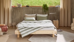 Chambre moderne avec un lit en bois et du linge de lit rayé.