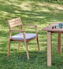 Eleganter Gartenstuhl aus Holz neben einem Tisch.