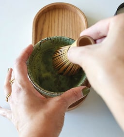 Matcha-Tee wird mit einem Bambusbesen in einer Schale aufgeschäumt.