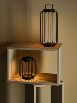 Deux lanternes noires dans une étagère projettent des rayons lumineux.