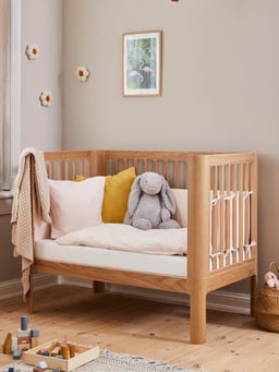Lapin en tissu dans un sac de couchage avec peluche et couverture dans un lit de bébé.