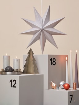 Calendario dell&apos;Avvento con stella argentata, candele e decorazioni natalizie.