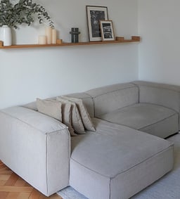 Un salon confortable avec un canapé gris et des éléments décoratifs sur une étagère murale.