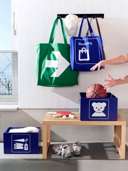 Boîtes de rangement, chaussures de sport, sacs et un ballon de basket sur un banc.