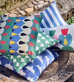 Une pile de coussins colorés avec différents motifs repose sur une table en pierre.