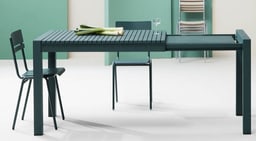 Ein minimalistischer grüner Tisch mit zwei grünen Stühlen und Lauch als Dekoration in einem modernen Raum.