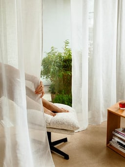 Moment de détente derrière des voilages blancs.
