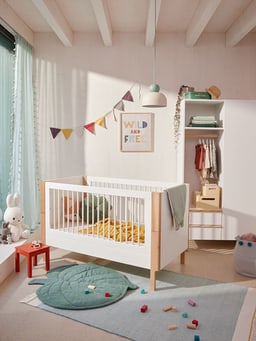Chambre d&apos;enfant confortable avec lit à barreaux, décorations colorées et jouets au sol.