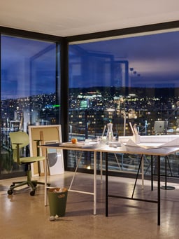 Modernes Büro mit großem Fensterblick auf die nächtliche Stadtbeleuchtung.